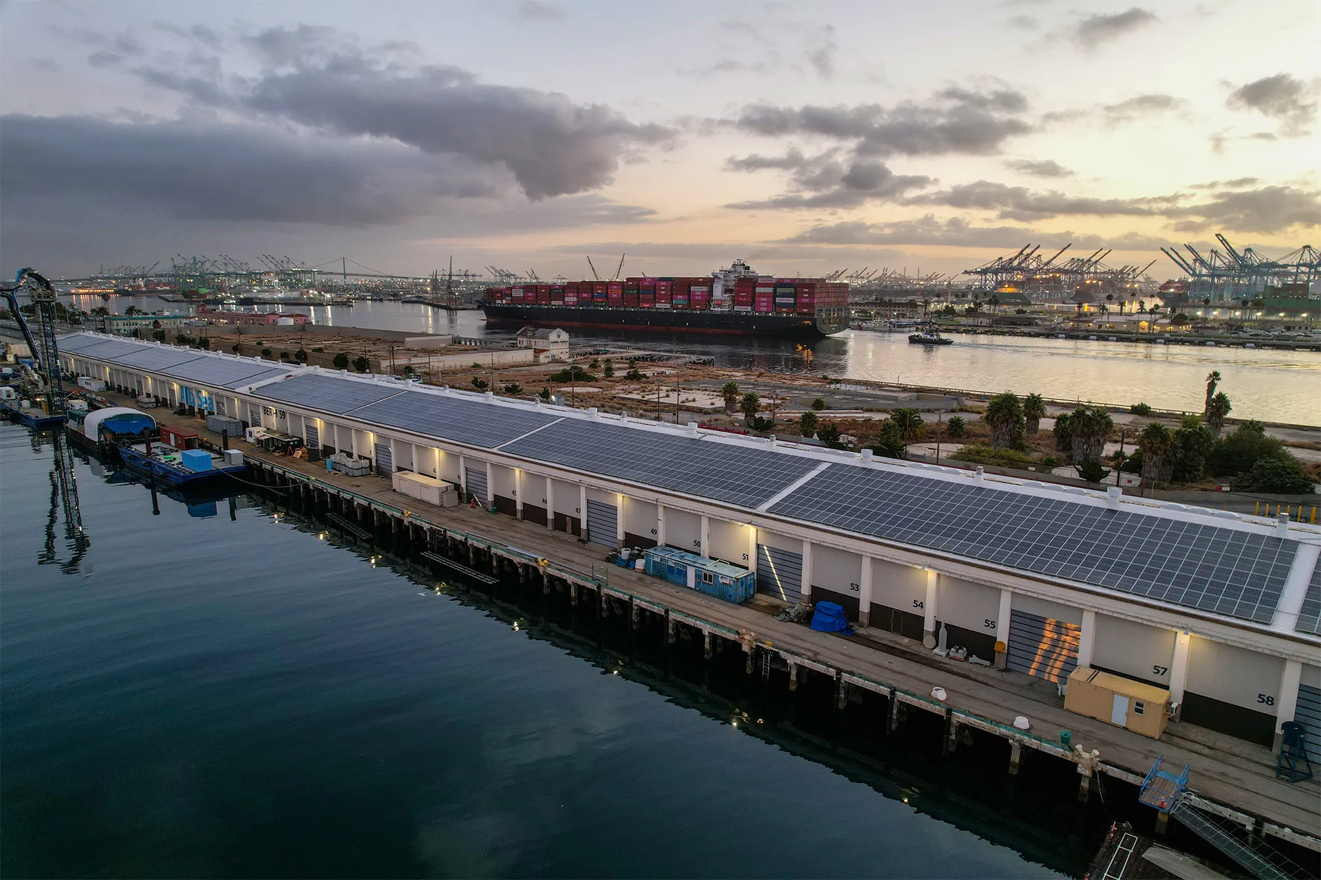 Aerial view of the AltaSea industrial research facility at the Port of Los Angeles with a cargo ship docked alongside.
