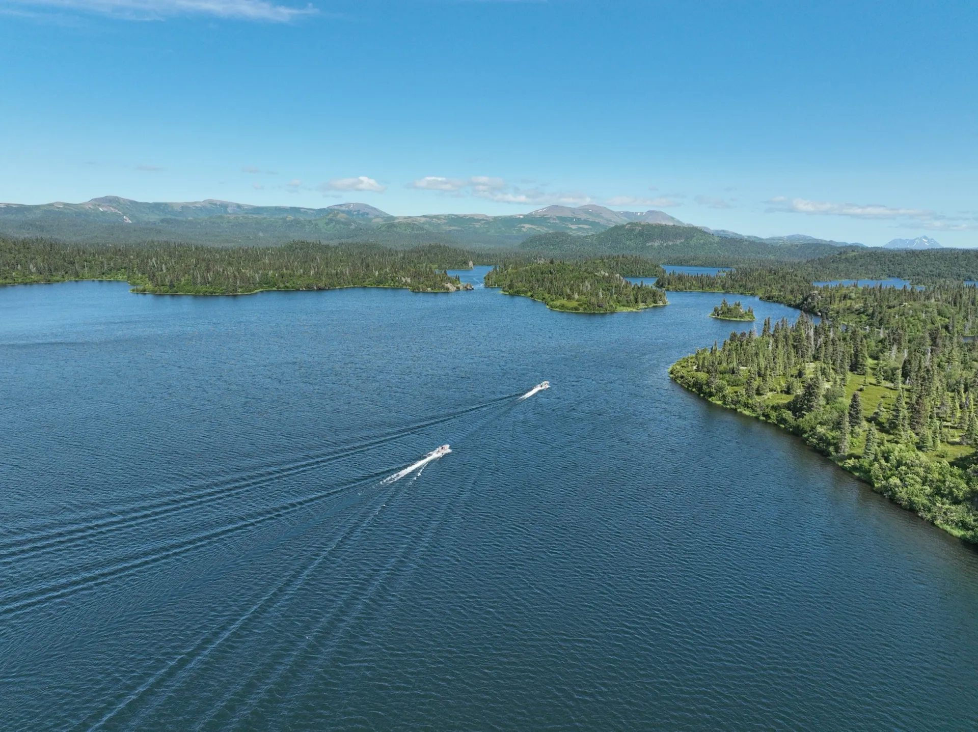 Aerial view of Legend Lodge on the shore of Lake Iliamna, Alaska, with structures, water, and surrounding landscape visible.
