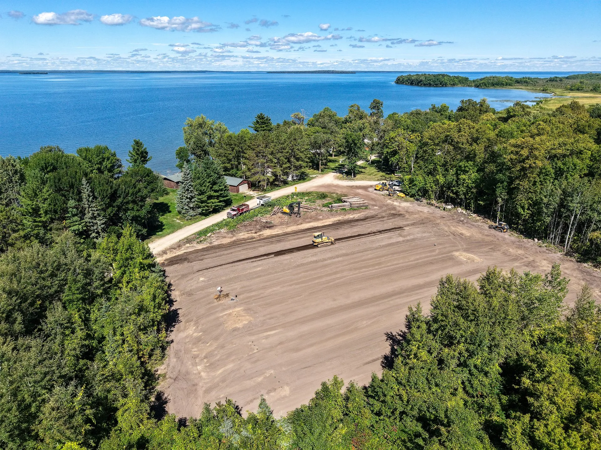 Aerial view of a Shepard Excavating site-prep job on the south shore of Leech Lake near Walker, Minnesota, with the graded lot, surrounding forest, and the lake behind it.