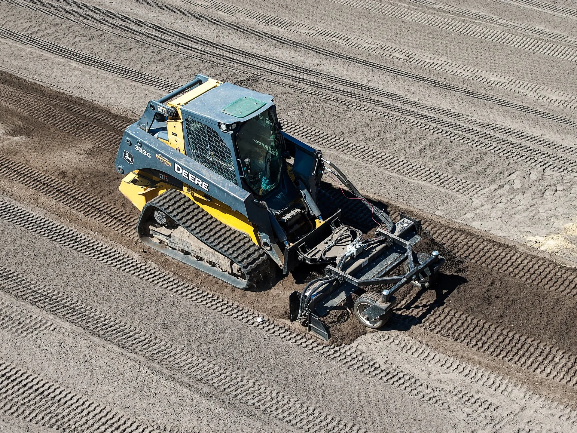 Top-down aerial view of a Shepard Excavating compact track loader grading a freshly prepared lot near Walker, Minnesota.